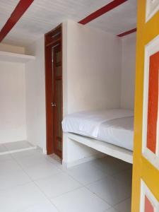 ein Schlafzimmer mit einem weißen Bett und einer Holztür in der Unterkunft Eco Hostal La Batea De Los Colibries in Cali