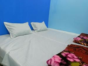 a large white bed with two pillows and a blanket at M Baba Guest House in Ujjain