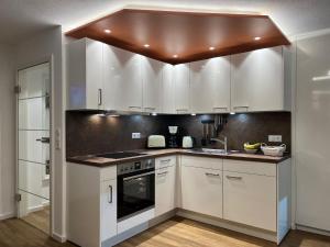 a kitchen with white cabinets and a brown ceiling at Alpenflair Ferienwohnungen Whg 236 in Oberstdorf