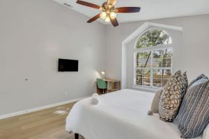 a white bedroom with a ceiling fan and a window at Paradise on the Islands in Savannah