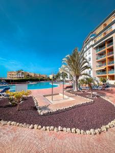a resort with a pool and palm trees and a building at Attico 512 - Golf del Sur in San Miguel de Abona