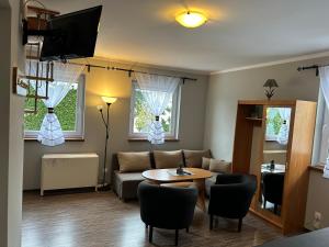 - un salon avec un canapé, une table et 2 fenêtres dans l'établissement Apartamenty Antonio, à Kudowa-Zdrój