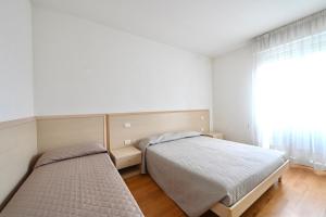 - une chambre avec 2 lits et une fenêtre dans l'établissement Tiepolo Apartments, à Lido di Jesolo