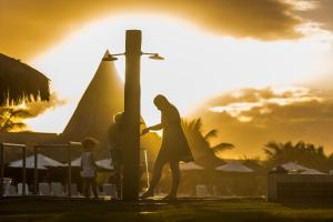 Una donna in piedi accanto a una croce al tramonto di Vila Galé Resort Marés - All Inclusive a Guarajuba