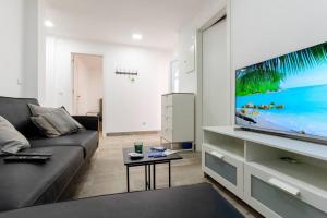 een woonkamer met een bank en een grote tv bij Casa Escondida in Grândola