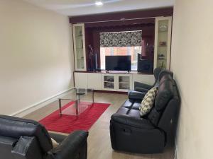 a living room with two leather chairs and a glass table at Spacious home for contractors and families in Sherborne Saint John
