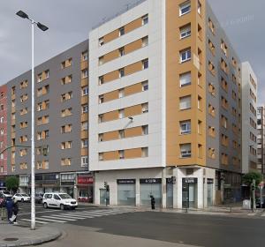 un gran edificio en una calle de la ciudad con coches aparcados en Atractivo piso recién reformado en Santander