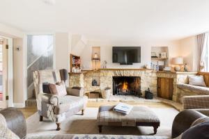 a living room with a stone fireplace with a tv at *COTSWOLDS CORNER COTTAGE* Nr Stow-on-the-Wold in Lower Swell