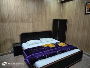 a bed in a room with a wooden wall at Silver Dew Resorts and Restaurant in Dhanaulti