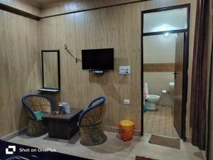 a bathroom with two chairs and a tv and a toilet at Silver Dew Resorts and Restaurant in Dhanaulti