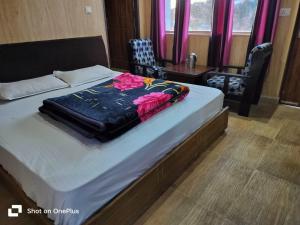 a bed with a blanket on it in a bedroom at Silver Dew Resorts and Restaurant in Dhanaulti