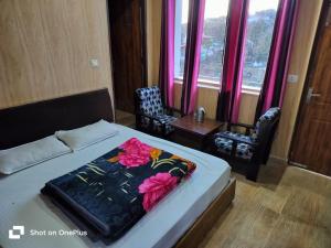 a bedroom with a bed and two chairs and a window at Silver Dew Resorts and Restaurant in Dhanaulti