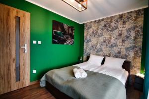 een groene slaapkamer met een bed en een groene muur bij Apartamenty Laguna Beskidów - A85 in Zarzecze