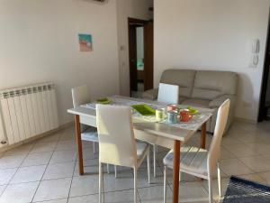 un tavolo da pranzo con sedie bianche e un divano di Palazzo Azzurro a Bassacutena