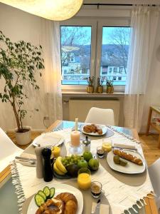 einen Tisch mit Teller mit Lebensmitteln und Obst darauf in der Unterkunft Boutique L´AHRpartement Ahr-Terrasse-Zentral in Bad Neuenahr-Ahrweiler