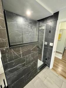 y baño con ducha y paredes de mármol negro. en 5 Bed / 3 bath Apt Near Jiminy Peak Berkshires, en Stephentown