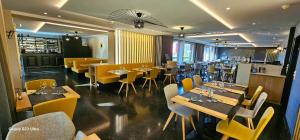 a restaurant with wooden tables and yellow chairs at Hotel Les 3 Cles in Gembloux