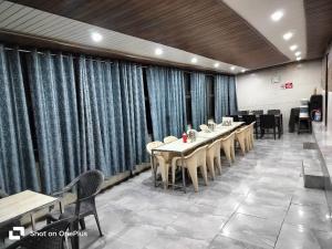 a dining room with tables and chairs and curtains at Silver Dew Resorts and Restaurant in Dhanaulti