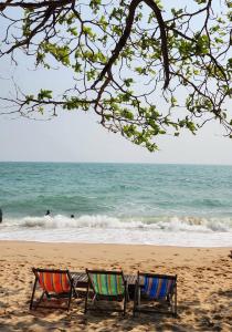 duas cadeiras sentadas na praia perto do oceano em KhaoTao Homestay เขาเต่าโฮมสเตย์ em Khao Tao