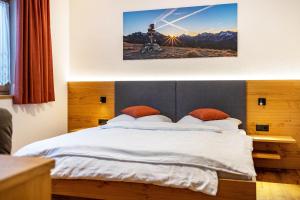 sypialnia z dużym łóżkiem z białą pościelą i pomarańczowymi poduszkami w obiekcie App Hubertus - Sonnklar w mieście Sand in Taufers