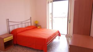1 dormitorio con cama de color naranja y ventana grande en SanMarco Holiday Home en Ascea