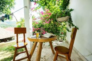 einen Tisch und zwei Stühle auf einer Veranda mit Blumen in der Unterkunft Ecohotel Mar de Prado in Prado