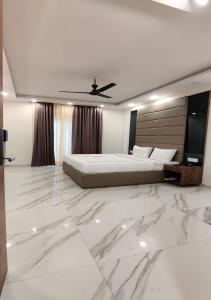 ein großes weißes Schlafzimmer mit einem Bett und einem Marmorboden in der Unterkunft PK Boutique Hotel in Noida