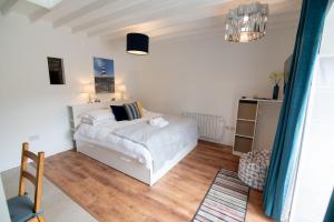 1 dormitorio con cama blanca y suelo de madera en Kilpatrick Glebe, en Crossabeg