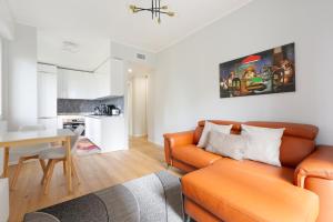 a living room with an orange couch and a kitchen at GuestHost - Cimiano M2 Balcony Apartment in Milan