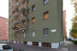 a green building with windows and balconies on a street at GuestHost - Cimiano M2 Balcony Apartment in Milan