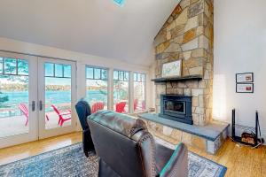 a living room with a couch and a stone fireplace at Maine Waterfront Luxury Retreat 