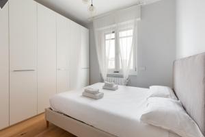 a white bedroom with a bed and a window at GuestHost - Cimiano M2 Balcony Apartment in Milan
