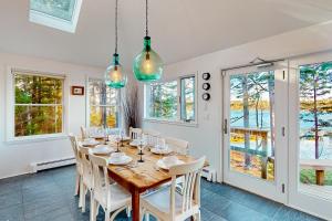 uma sala de jantar com mesa, cadeiras e janelas em Maine Waterfront Luxury Retreat 