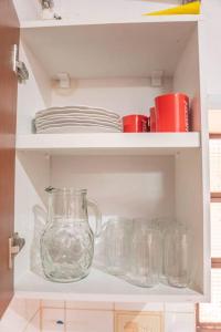 um armário branco com vasos de vidro e pratos em Hermosa casa de 3 dormitorios em Encarnación