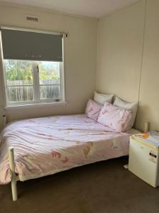 Warrane的住宿－Jennifer，一间卧室配有一张带粉色床单的床和一扇窗户。