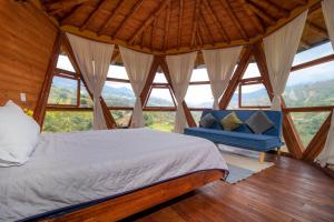 a bed and a blue couch in a room with windows at Glamping Corazón del Molino in Ubaque