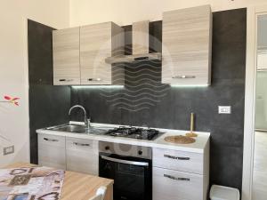 een keuken met een fornuis top oven naast een tafel bij Marks House - Spiaggia a 300m By Cala Salento in Porto Cesareo