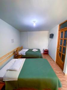 a room with two beds and a television in it at Chacraraju Hostel in Huaraz