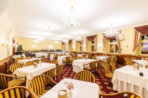 a restaurant with white tables and chairs and chandeliers at Grandhotel Zvon in České Budějovice +21 photos