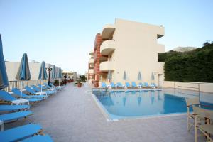 a hotel with a swimming pool with chairs and umbrellas at Elpis Studio Apartments in Balíon