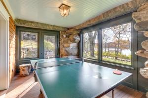 a ping pong table in a room with windows at Grand Lakefront Home in Warren with Expansive Patio! in Warren