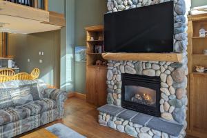 ein Wohnzimmer mit einem Steinkamin und einem Flachbild-TV in der Unterkunft Tree Tops 35 in Big White