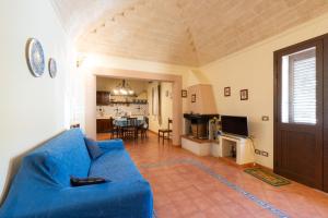 uma sala de estar com um sofá azul e uma cozinha em Casa Cris em Castelluzzo