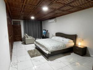 1 dormitorio con 1 cama y 1 silla en Amazing Grace Villa en Accra