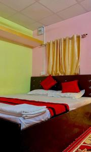 a bedroom with a bed with red pillows and a window at Sweet Home Lodge in Guwahati