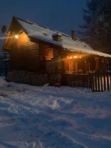 una casa cubierta de nieve por la noche con luces en Bieszczadzka Sielanka en Wojtkowa