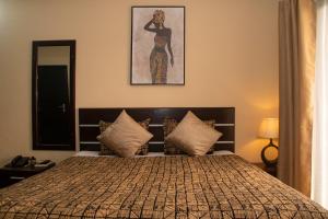 a bedroom with a bed with a picture on the wall at Enka Flat Hotel in Abidjan