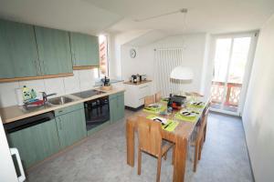 eine Küche mit grünen Schränken und einem Tisch mit Stühlen in der Unterkunft Villa Hartenfels 3 in Scuol