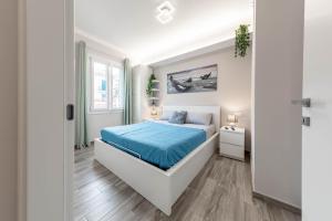een witte slaapkamer met een bed met blauwe lakens bij H11 [LUXURY SANREMO] Centro - Elegante - Casinò in Sanremo