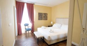 Algilà Firenze Luxury Apartments في فلورنسا: غرفة نوم بسرير وكرسي ونوافذ